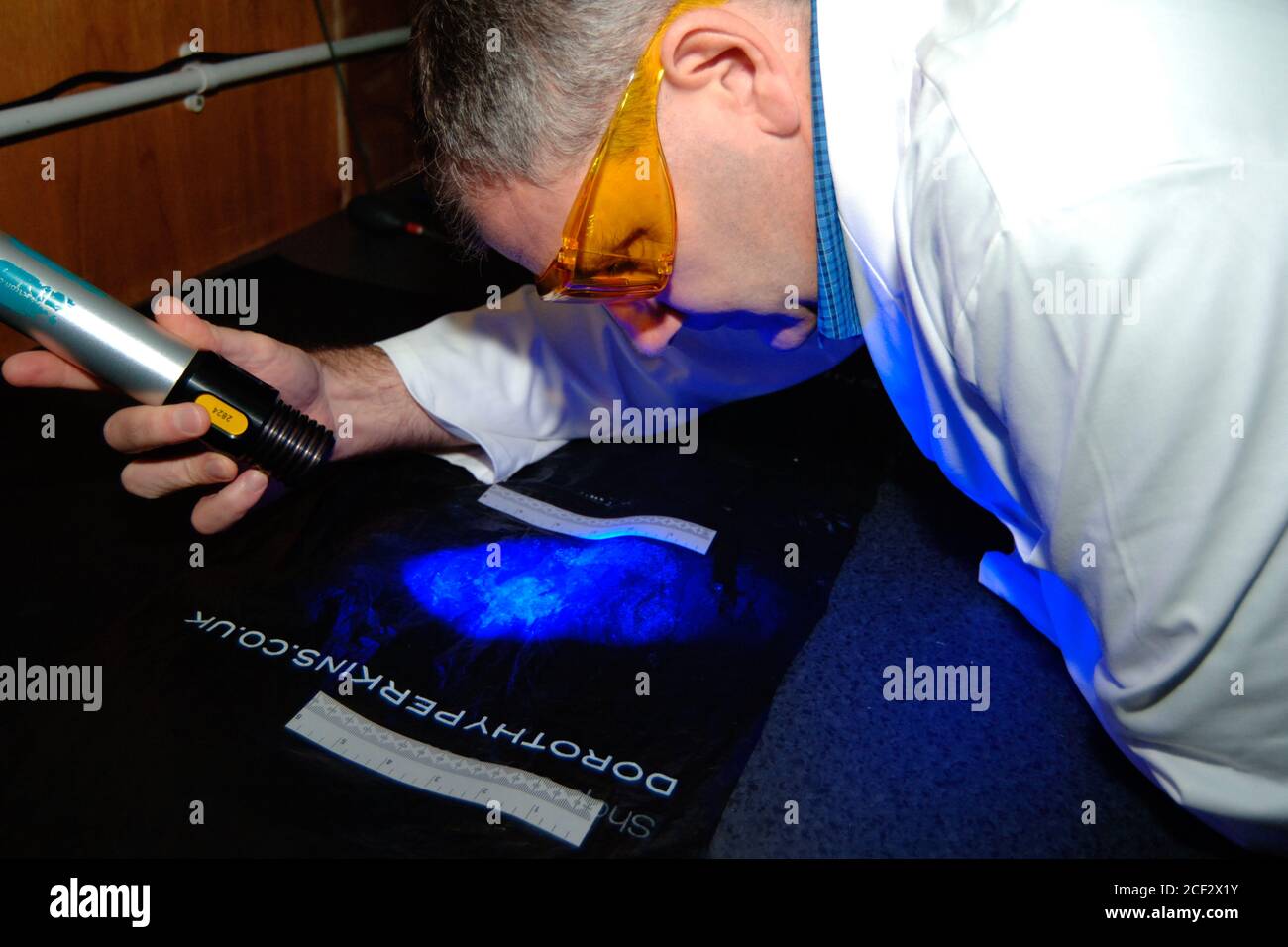 Forensic police officer searches for fingerprints on a plastic bag as