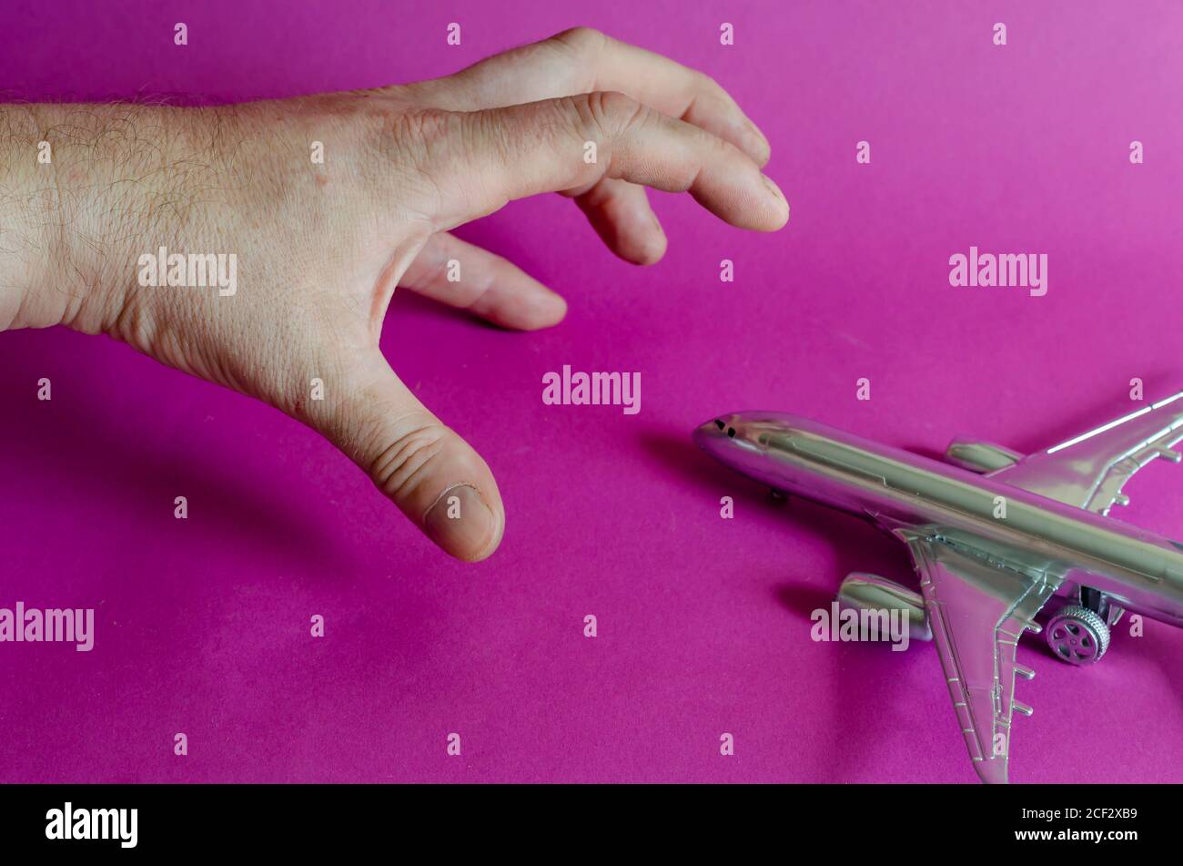 The hand tries to grab a model of the silver plane. A man's hand hangs ...