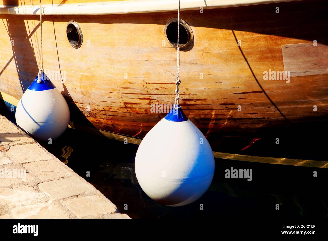 Wooden ship and bumpers for docking . Boat Fenders on the harbour Stock