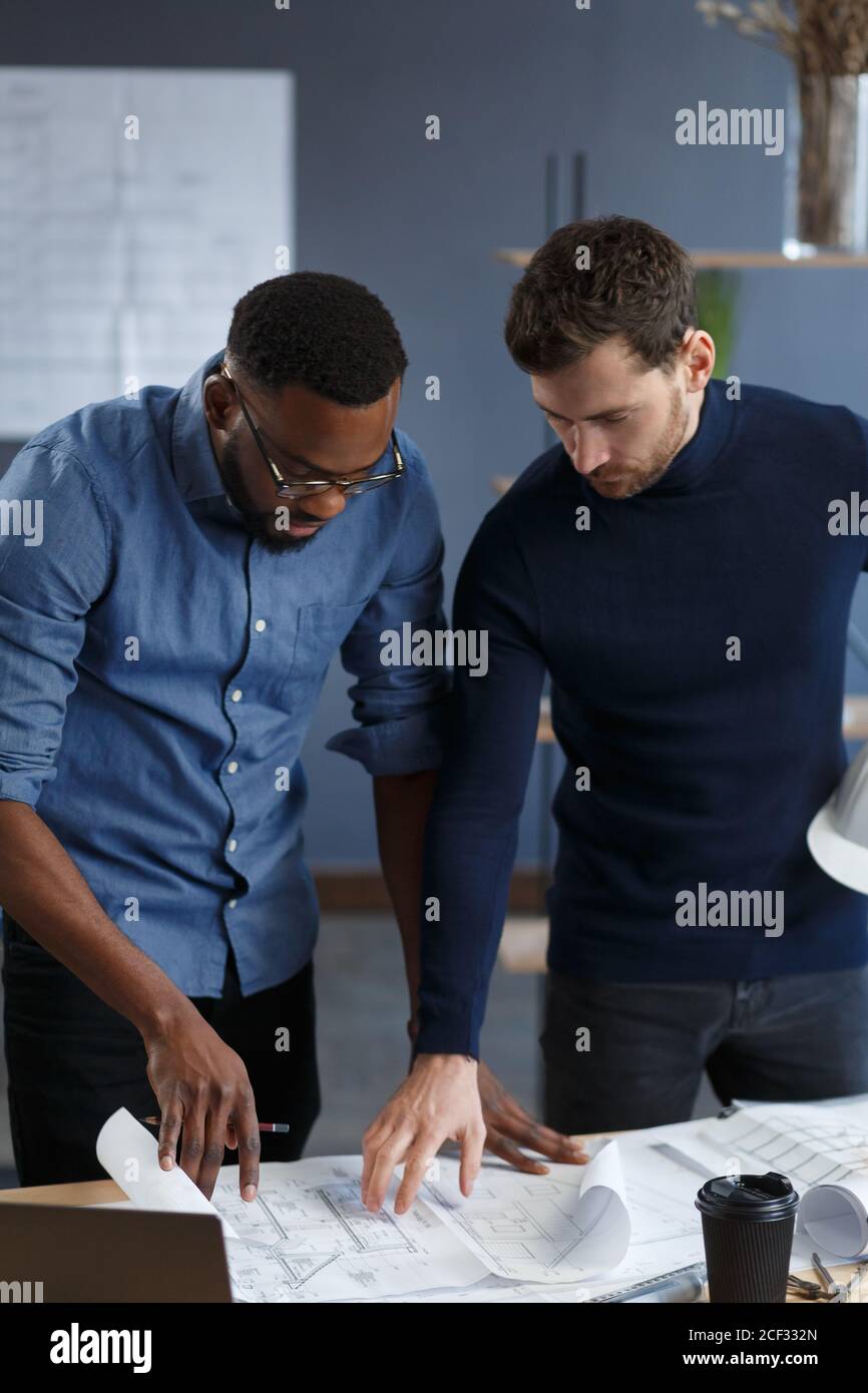 Multiracial engineer team working in office with blue prints and ...