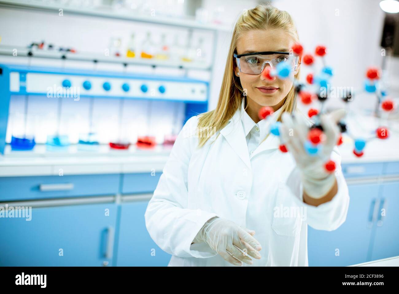 Female chemist with safety goggles hold molecular model in the lab Stock Photo