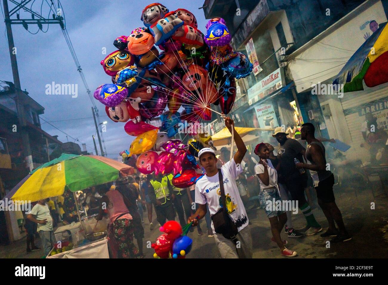 An AfroColombian balloon vendor walks in the street during the San
