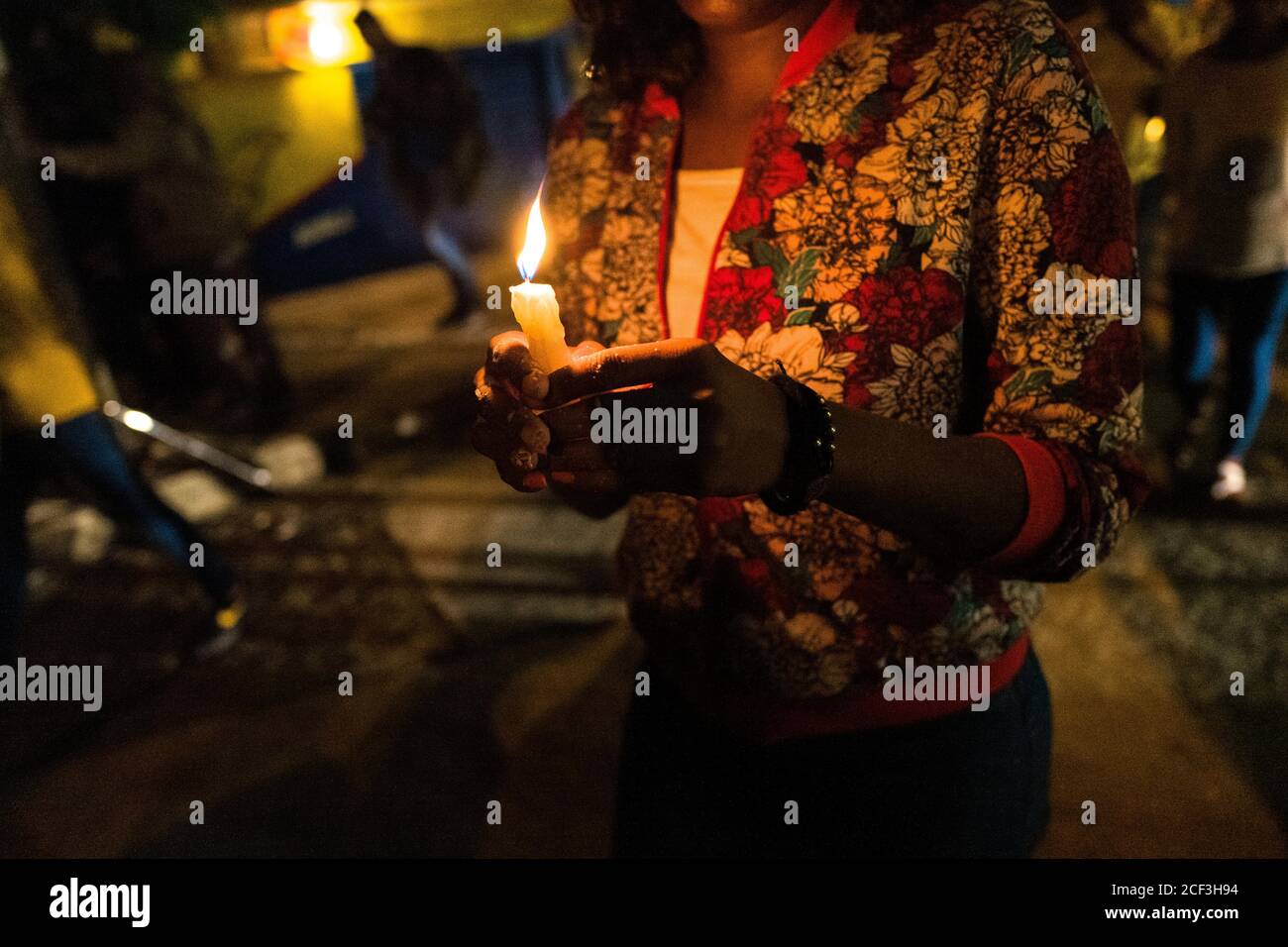 An Afro-Colombian Catholic follower holds a candle while taking part in a religious procession during the San Pacho festival in Quibdó, Colombia. Stock Photo