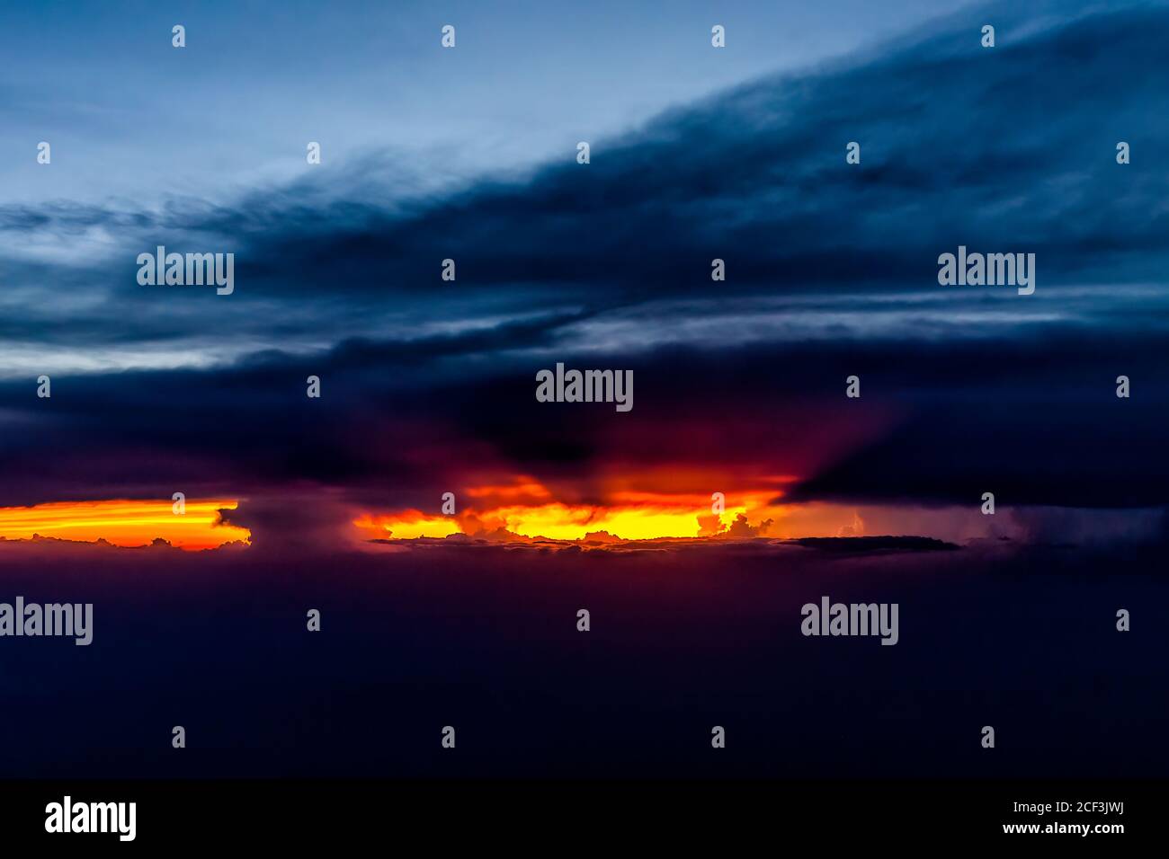 Colorful dramatic red dark sunset sun rays behind clouds in Virginia horizon high angle aerial view from airplane window from Dulles airport with skys Stock Photo