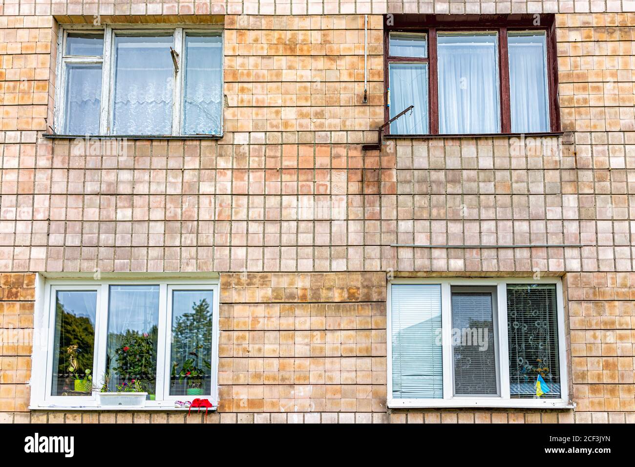 Windows on residential old soviet apartment building in Rivne, Ukraine with Ukrainian Flag and run-down wall and nobody Stock Photo