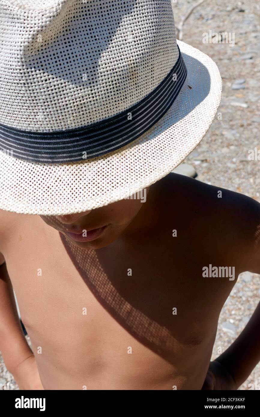 Portrait at the seaside with face of a young kid hidden by the hat's brim, close up Stock Photo