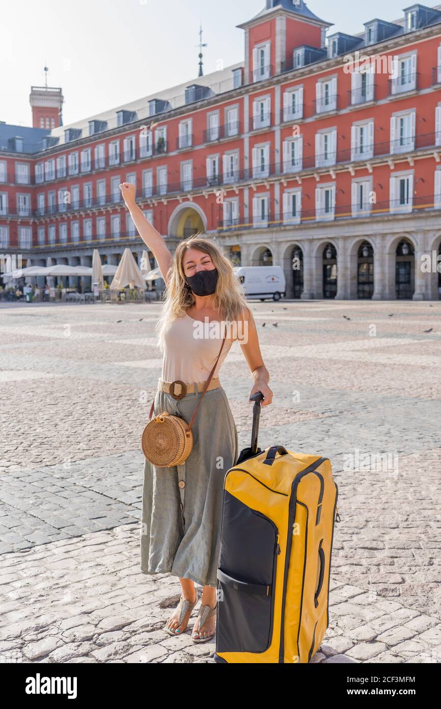 Young tourist woman wearing protective face mask happy and excited in Plaza Mayor Madrid Spain enjoying holidays in Europe after coronavirus outbreak Stock Photo