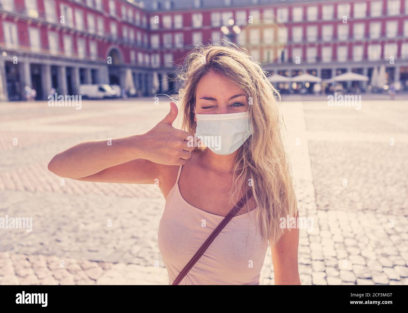 Young tourist woman wearing protective face mask happy and excited in Plaza Mayor Madrid Spain enjoying holidays in Europe after coronavirus outbreak Stock Photo