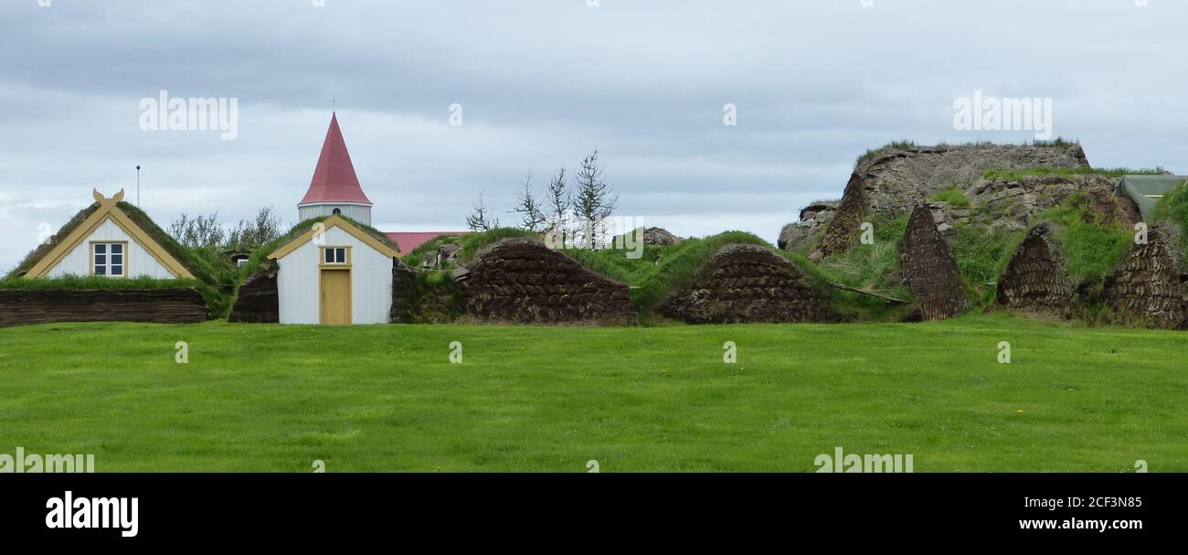 Small scenic village and green grass field  in Iceland. Idyllic icelandic landscape. Cool northern summer. Stock Photo