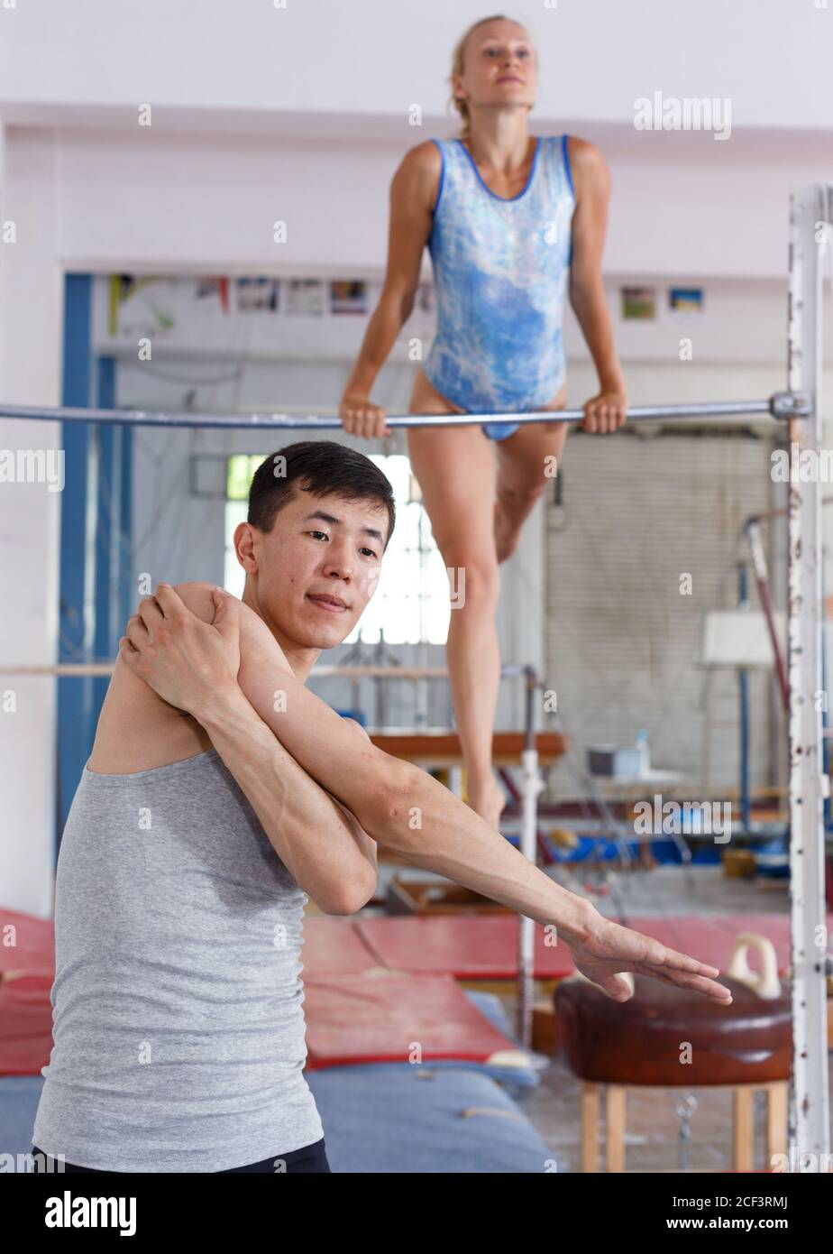 Sporty couple man and woman training on floor and on horizontal bar in ...