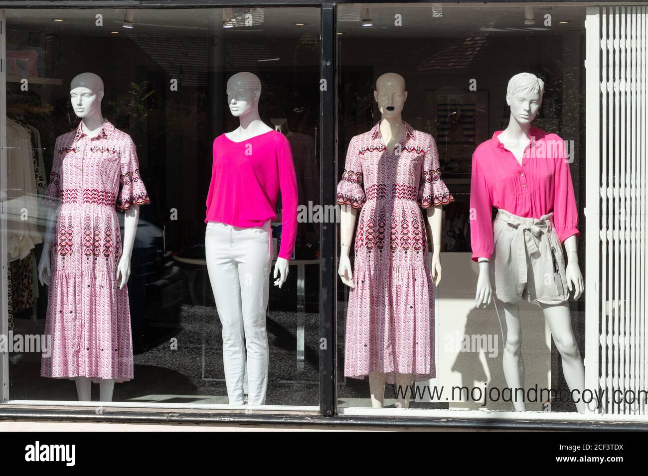 Mannequins dressed in pink clothes in the window display of an upmarket fashion shop Stock Photo