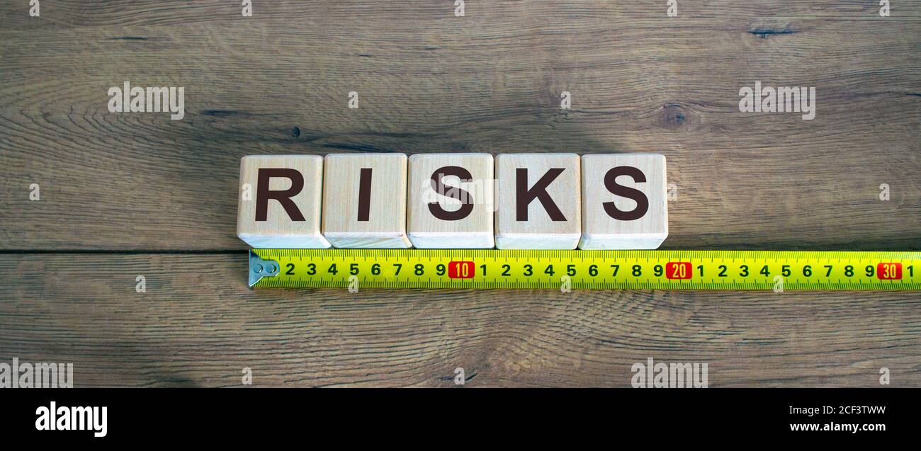 'Risks' word on blocks arranged behind the ruler on wooden table ...