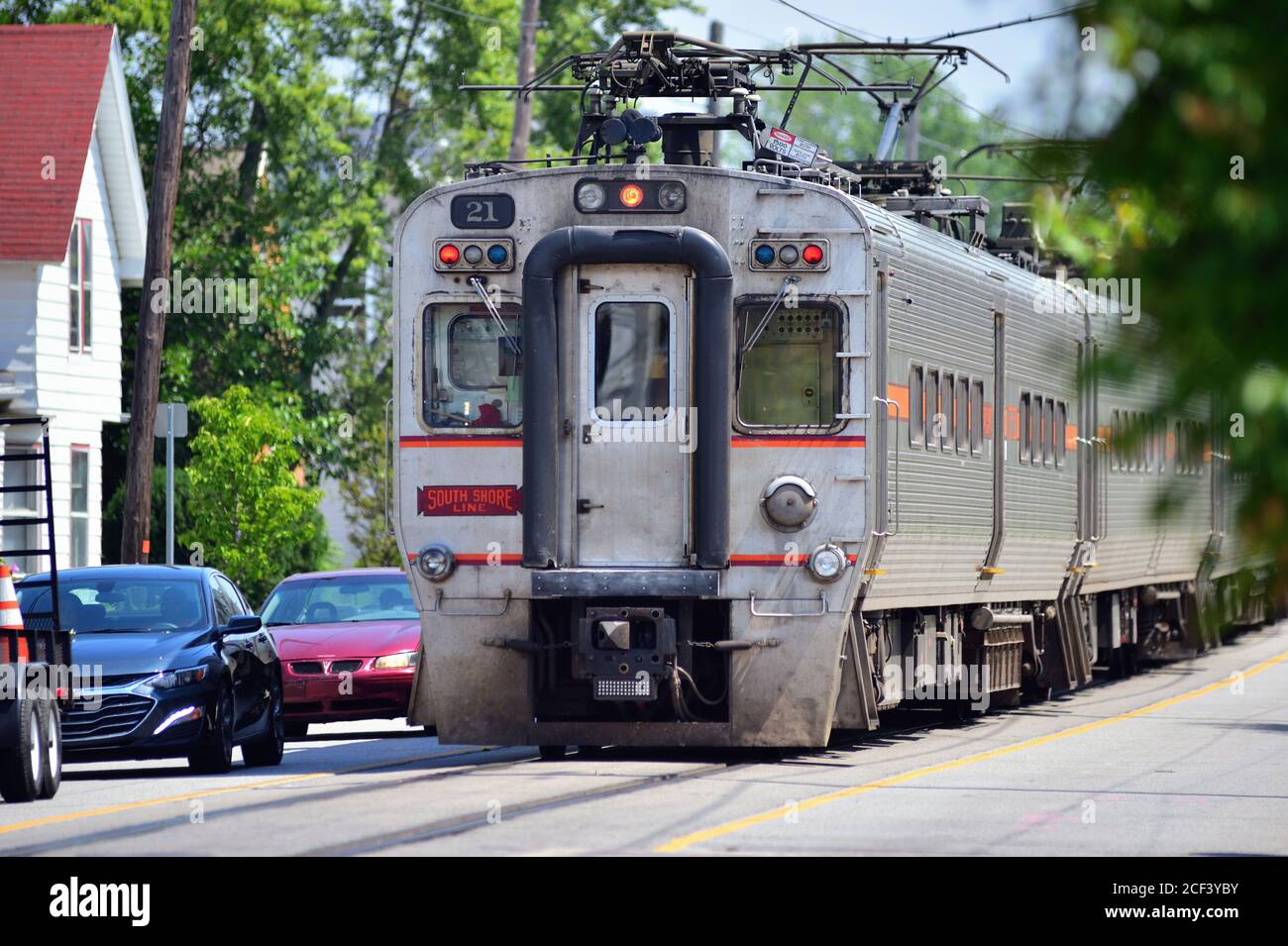 Michigan City, Indiana, USA. A South Shore line commuter train in the middle of 11th Street and traffic in Michigan City, Indiana. Stock Photo