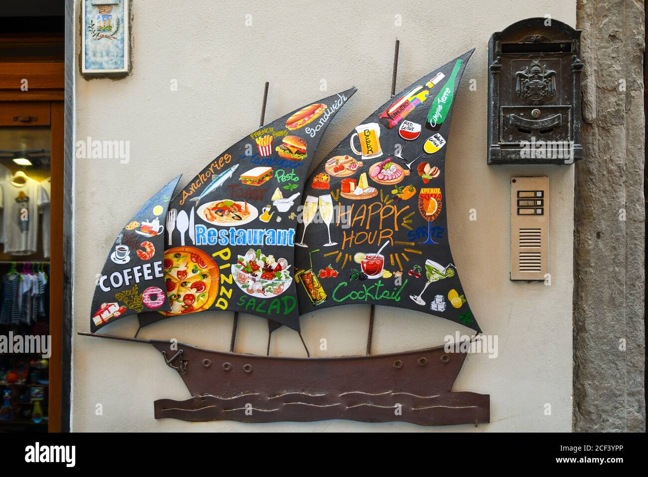 Close-up of a metal restaurant sign in the shape of a sail boat with paintings of different types of food and drinks, Porto Venere, La Spezia, Italy Stock Photo