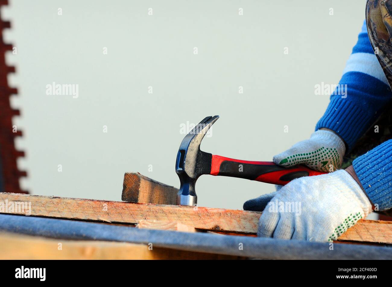 Contractor installing bitumen roof shingles with hammer and nails Stock
