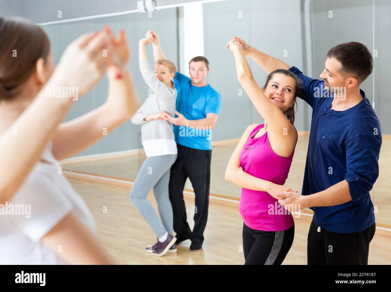 Group of happy adult people dancing modern social dances in pair at