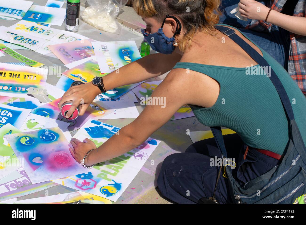 Stencil spraying using erasable chalk paint.Woman with spray paint can. Yin and Yang symbol and slogans. Extinction Rebellion protest Manchester, UK Stock Photo