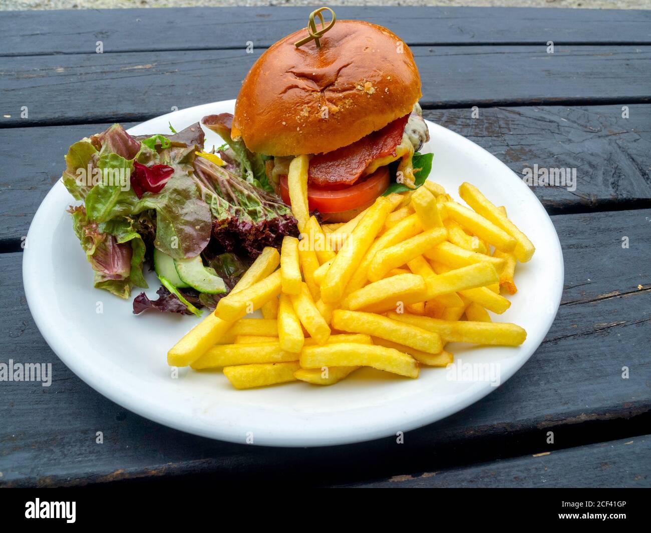 Lord Stones Café  lunch  a  prime Belted Galloway  beef burger  with melted cheddar cheese served outdoors with bacon chips and salad Stock Photo