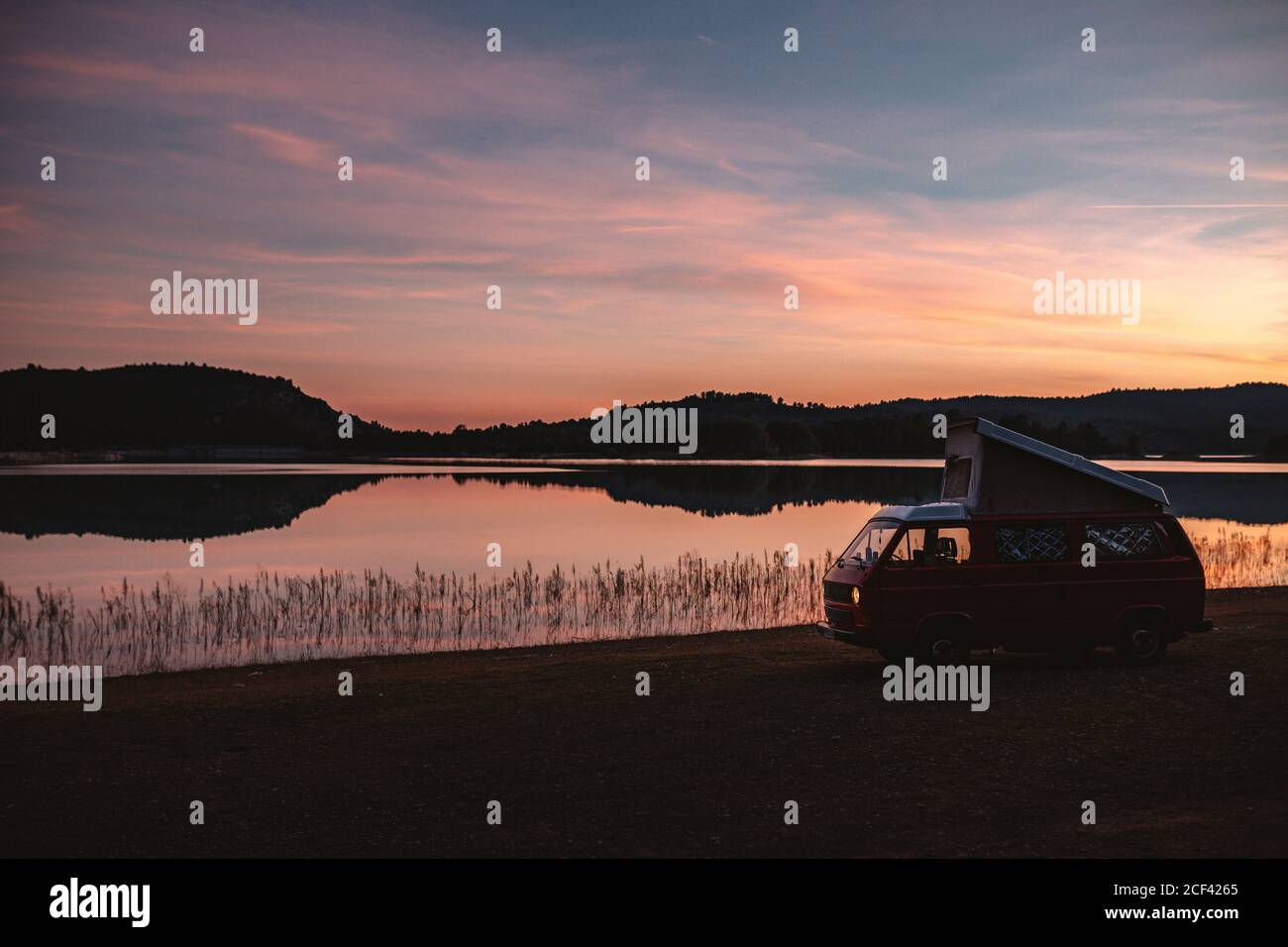 Empty van located on shore near tranquil lake during sundown in quiet countryside Stock Photo