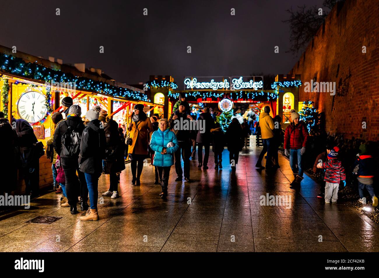 Warsaw, Poland - December 22, 2019: Old town Warszawa Christmas market near royal castle square people walking by entrance with illumination lights at Stock Photo
