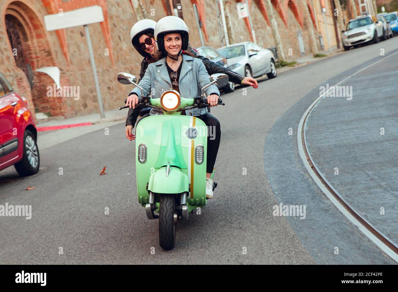 Green scooters with young people in motorcycle helmet driving in row on