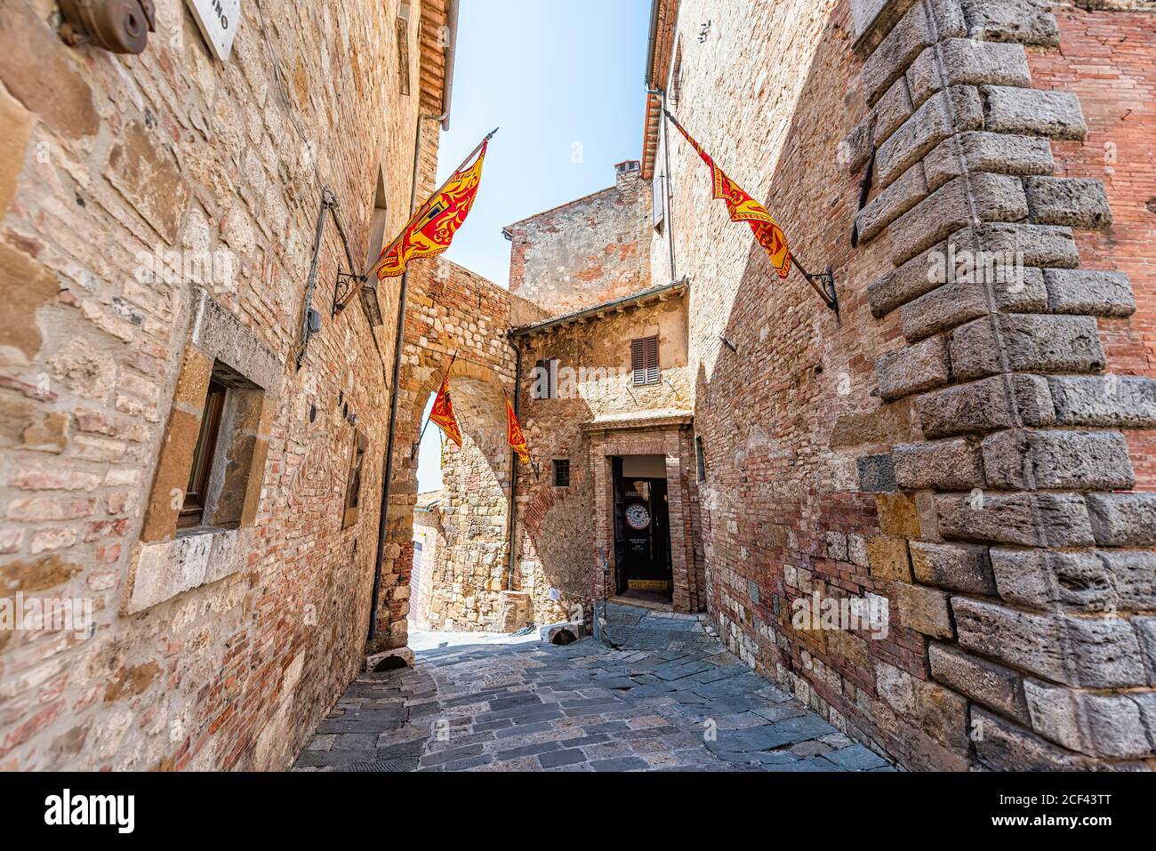 Montepulciano, Italy - August 28, 2018: Narrow alley empty street path in small town village in Tuscany with flags and entrance to laundry laundromat Stock Photo