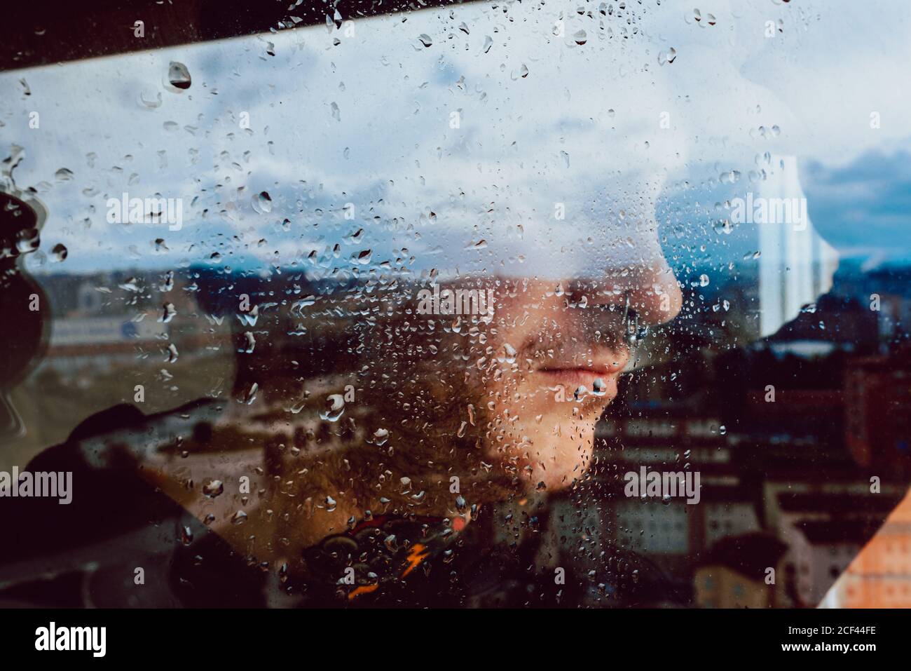 Depressed man looking through window Stock Photo