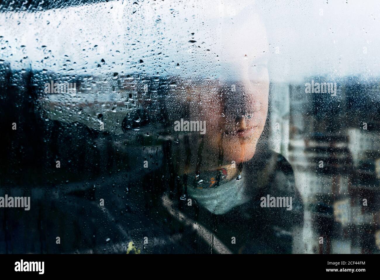 Depressed man looking through window Stock Photo