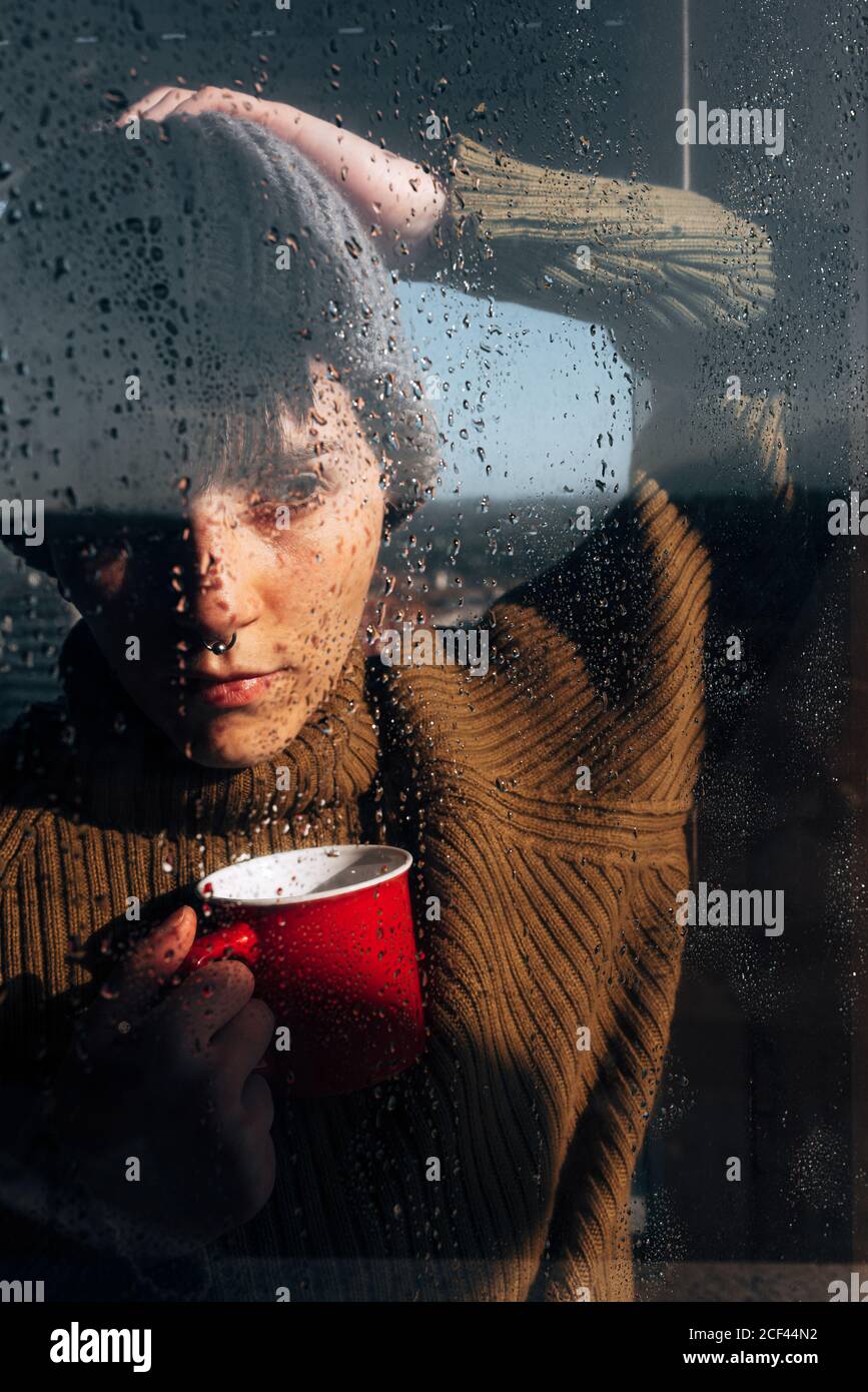 Thoughtful Woman drinking coffee near window Stock Photo