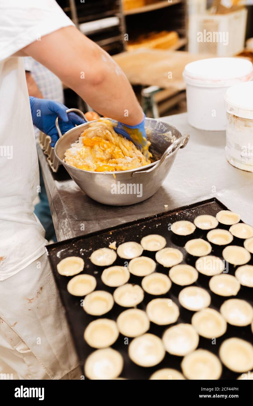 Crop confectioner in gloves and uniform mixing and kneading soft fresh