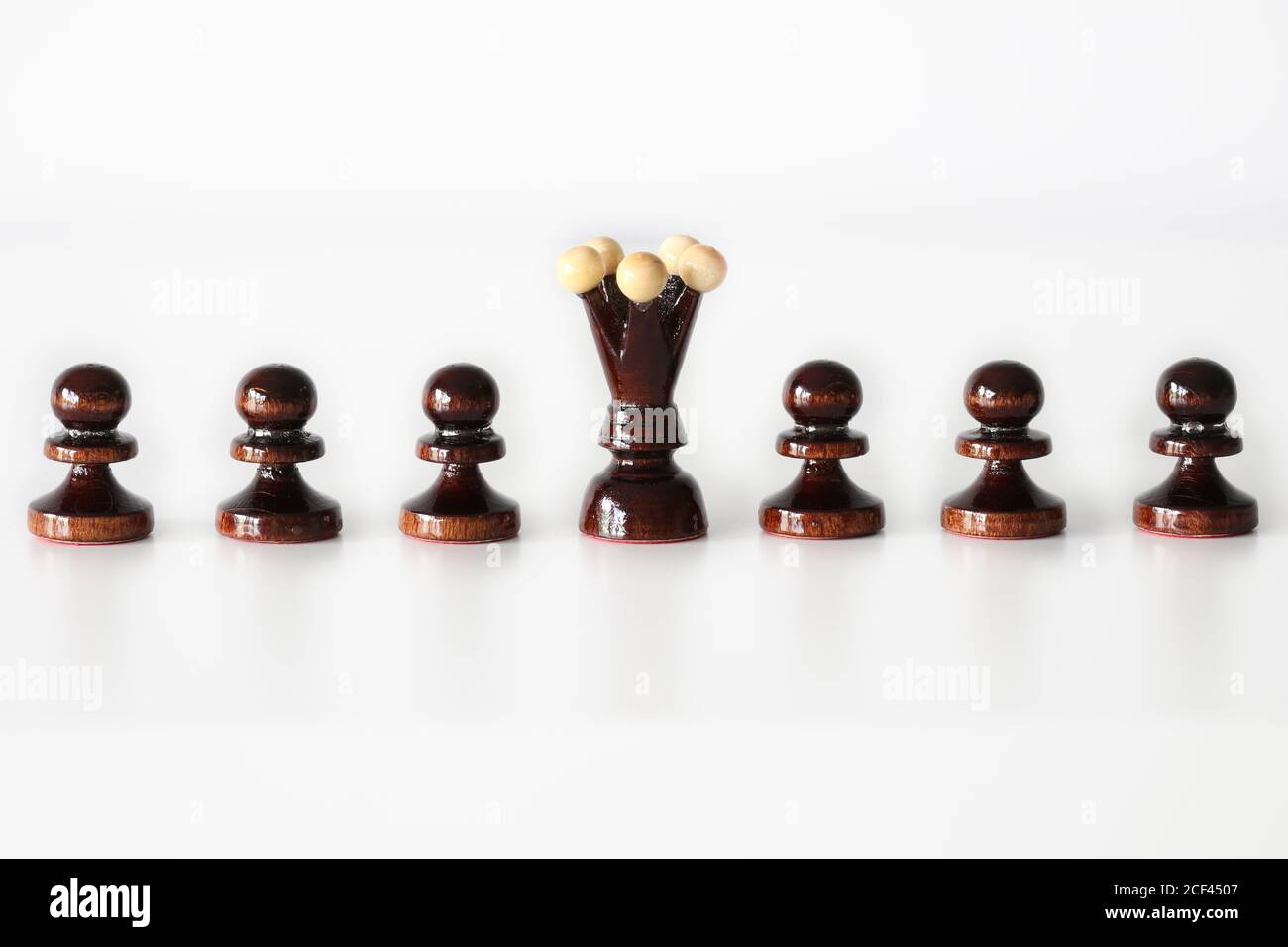 Row of black pawn chess pieces with queen in the middle on white background - stand out of the crowd concept Stock Photo