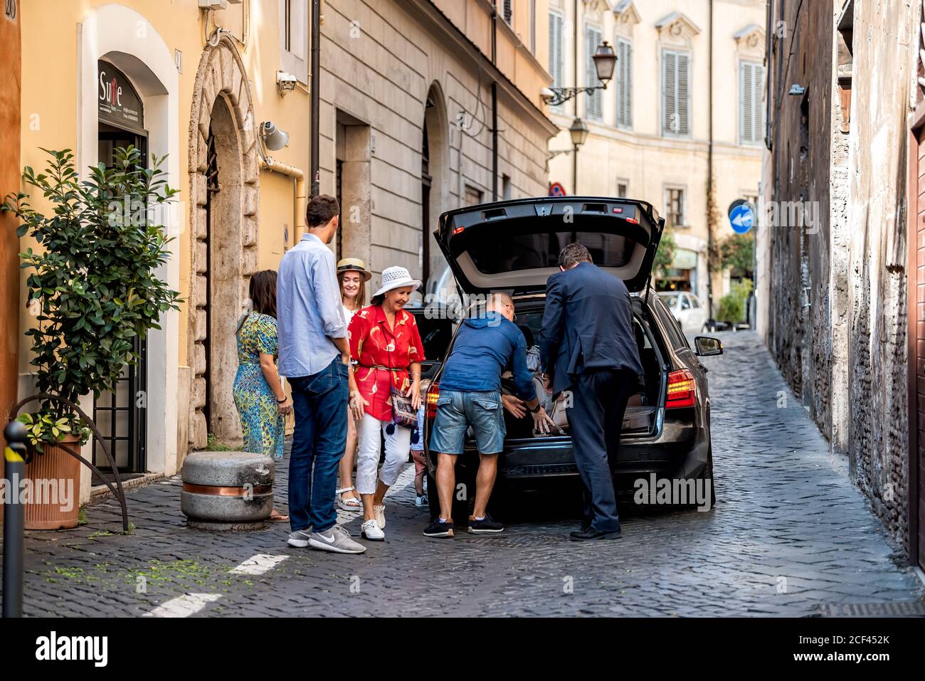 Rome, Italy - September 4, 2018: Narrow city town street by HiSuiteROME hotel with people departing taxi on road and family on Via di Monte Giordano Stock Photo