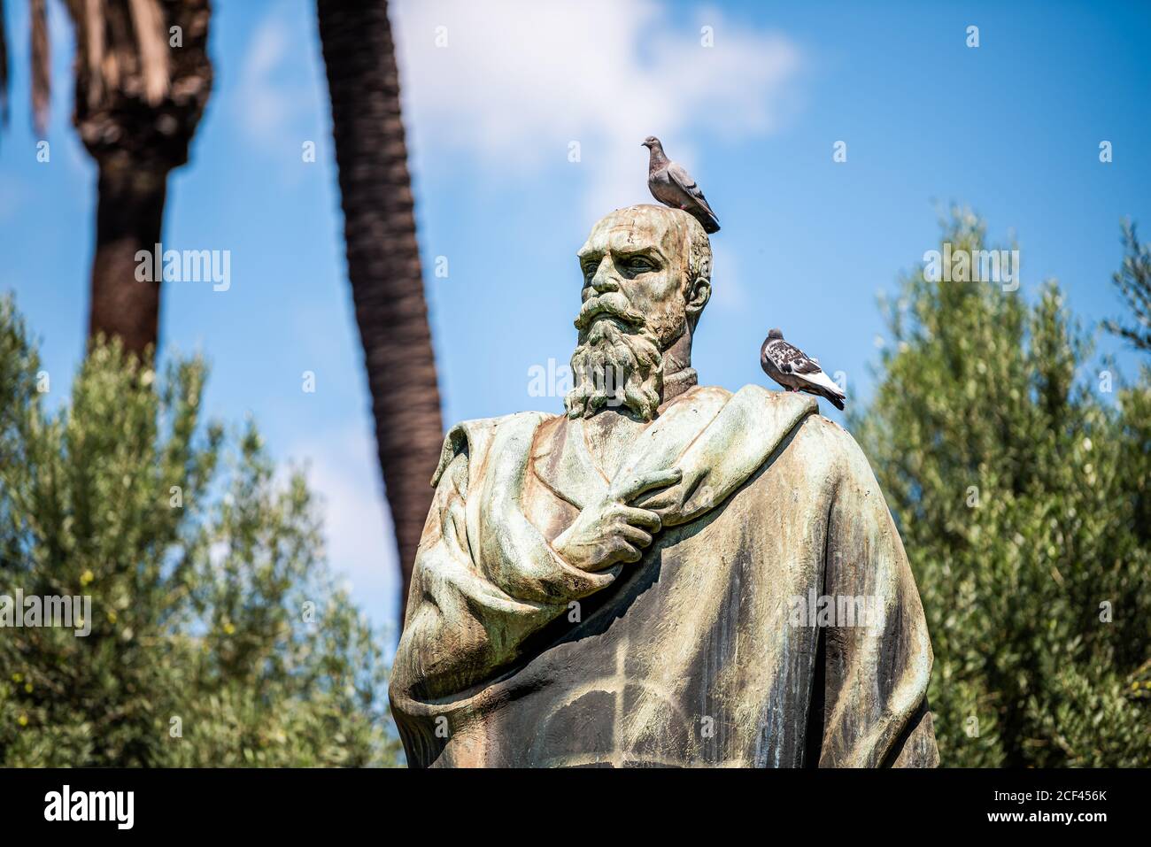 Rome, Italy - September 4, 2018: Historic green city park on Via della Domus Aurea street with statue of Alfredo Oriani and birds closeup blue sky Stock Photo