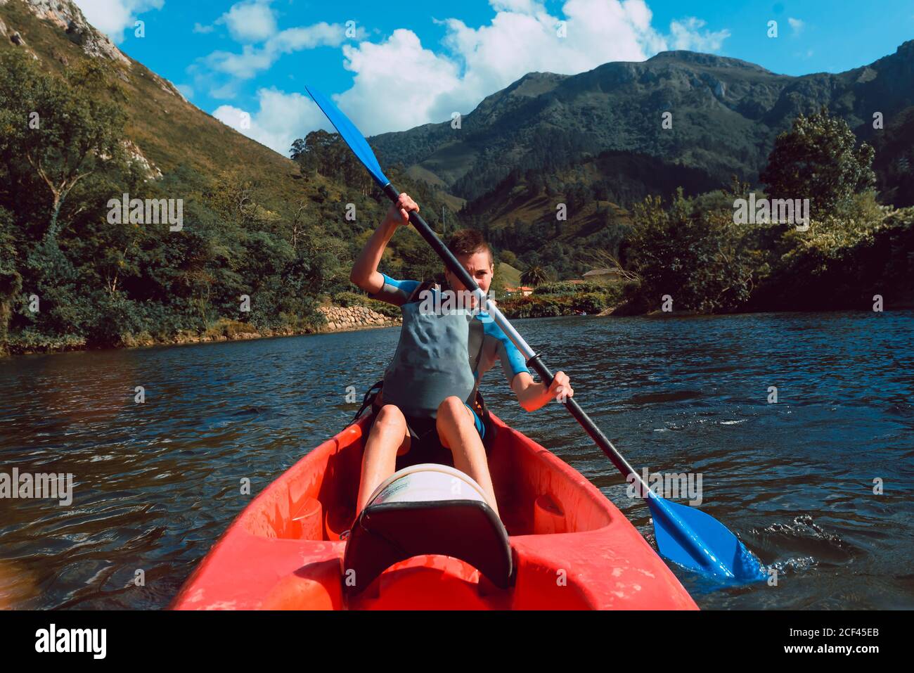 Sportive Woman sitting in red canoe and paddling on Sella river decline in Spain Stock Photo
