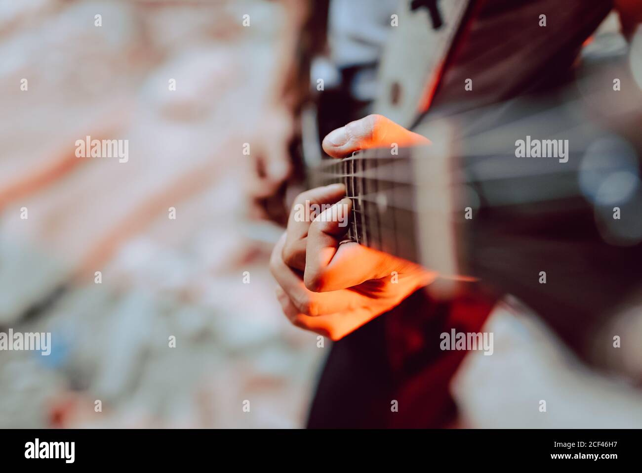 Soft focus of male musician clamping strings on guitar fret board while playing music Stock Photo