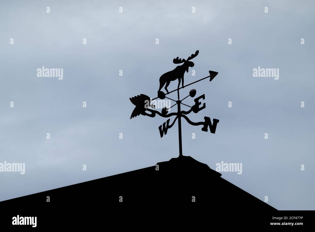 Silhouetted moose weather vane on top of a roof. Stock Photo