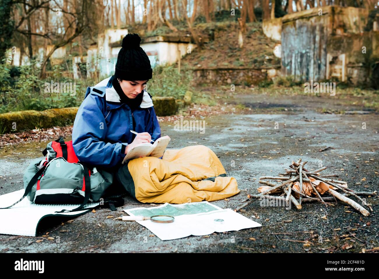 Young female backpacker making notes at campfire Stock Photo
