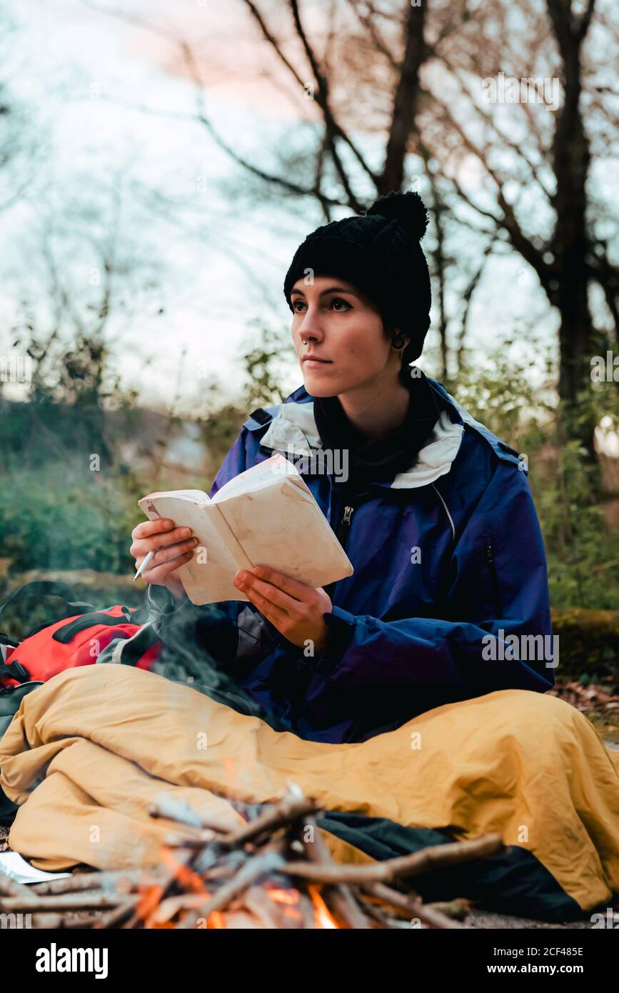 Young female backpacker making notes at campfire Stock Photo