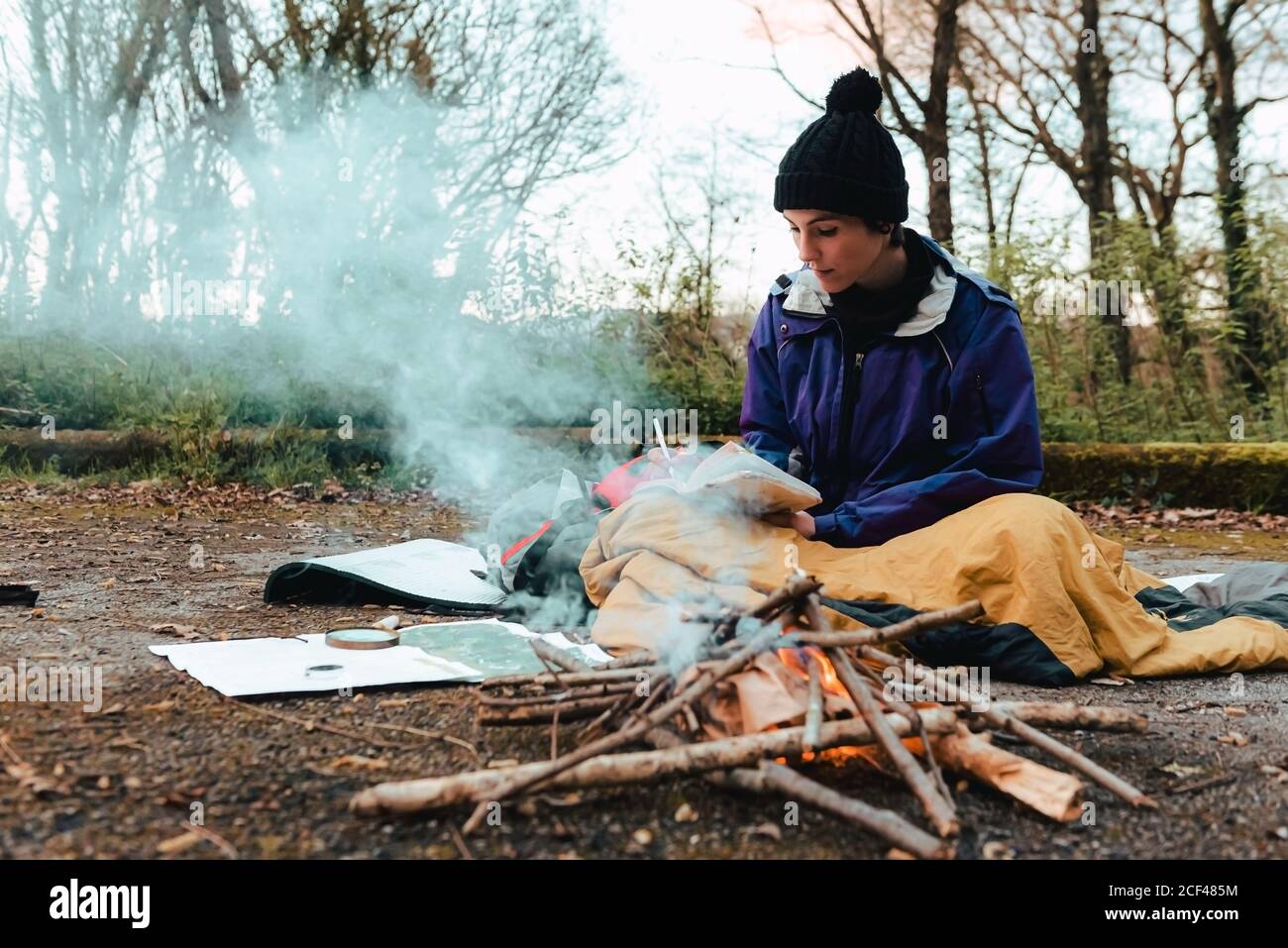 Young female backpacker making notes at campfire Stock Photo