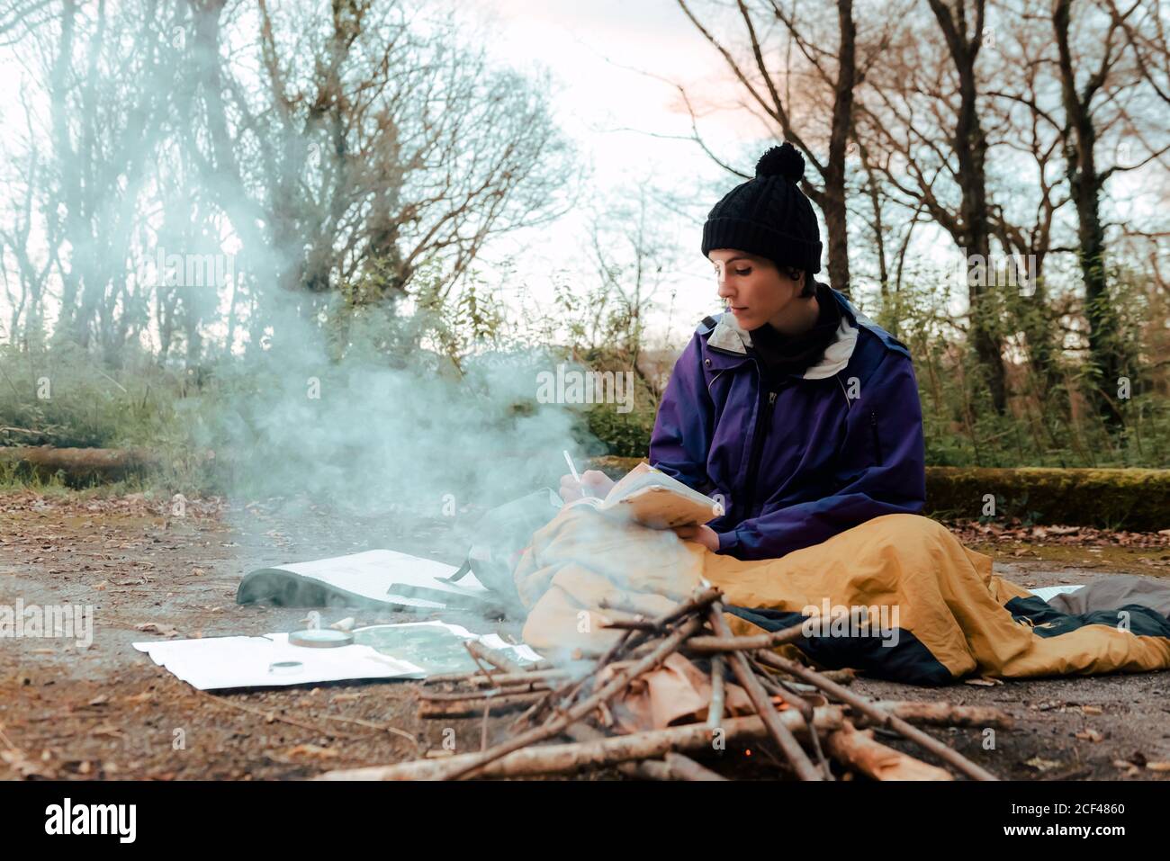 Young female backpacker making notes at campfire Stock Photo