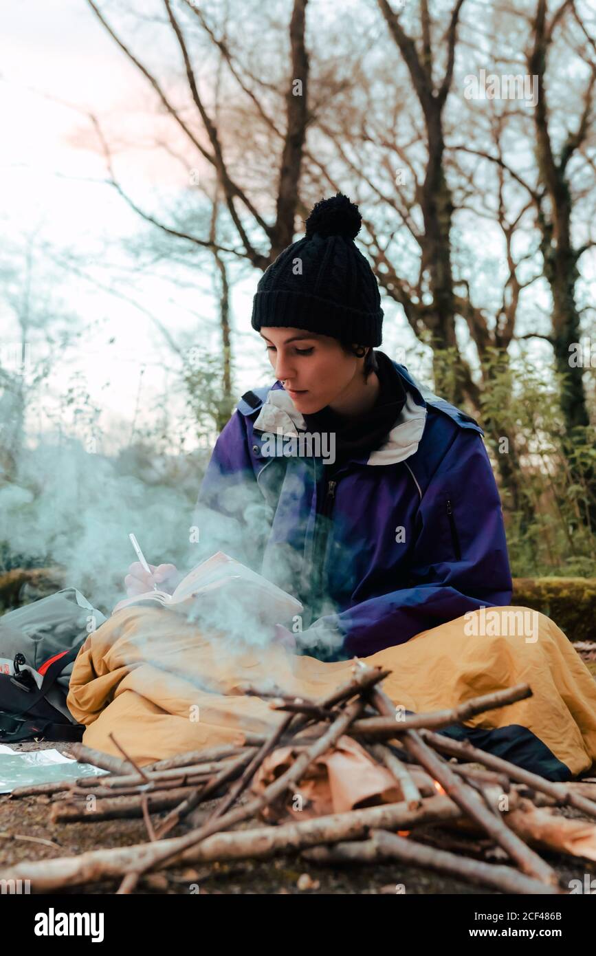Young female backpacker making notes at campfire Stock Photo
