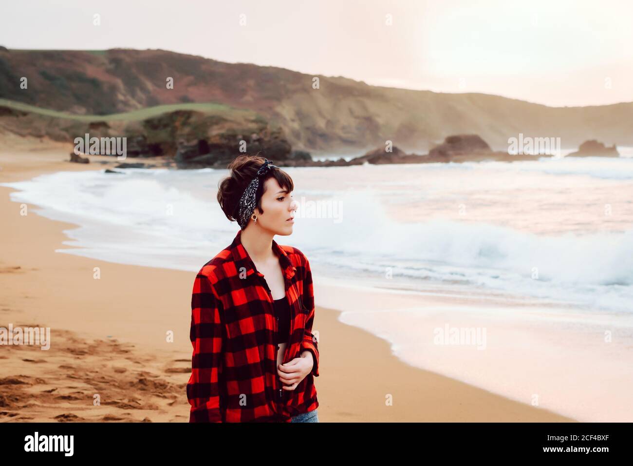 Woman standing on wet sand on beach Stock Photo
