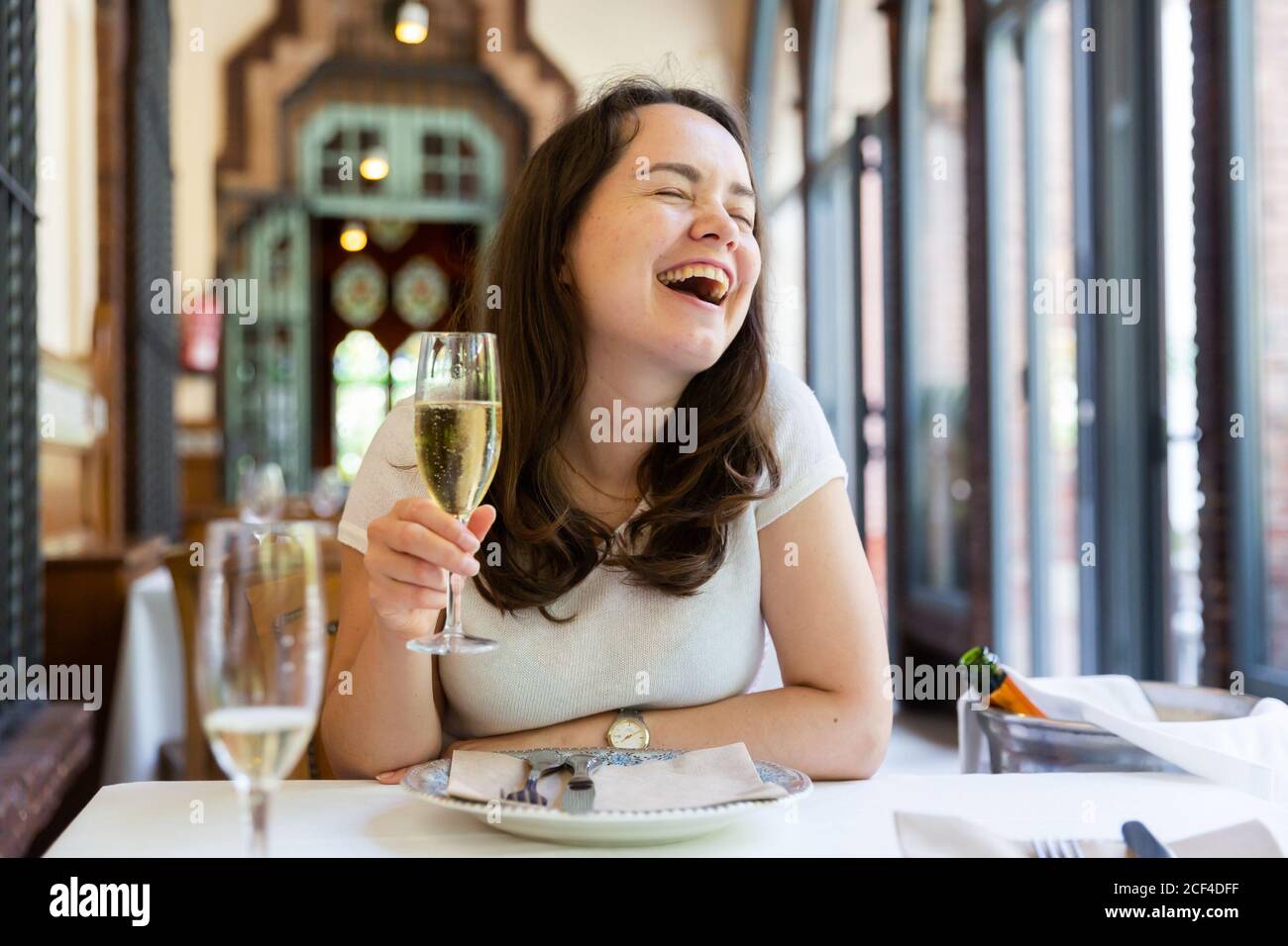 Portrait of slightly drunk laughing woman sitting at table in