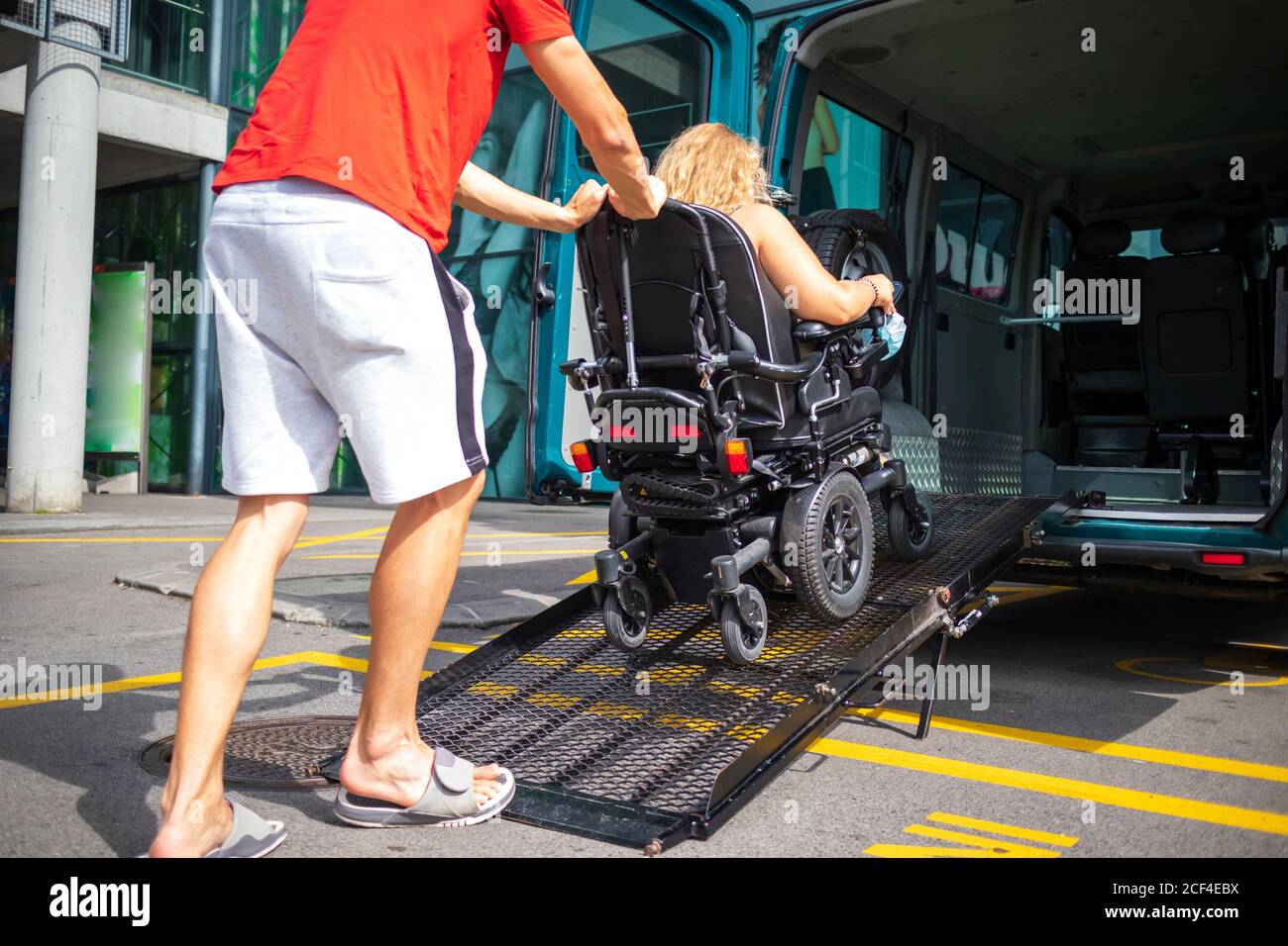 Woman on wheelchair using a vehicle ramp. Accessible transport with