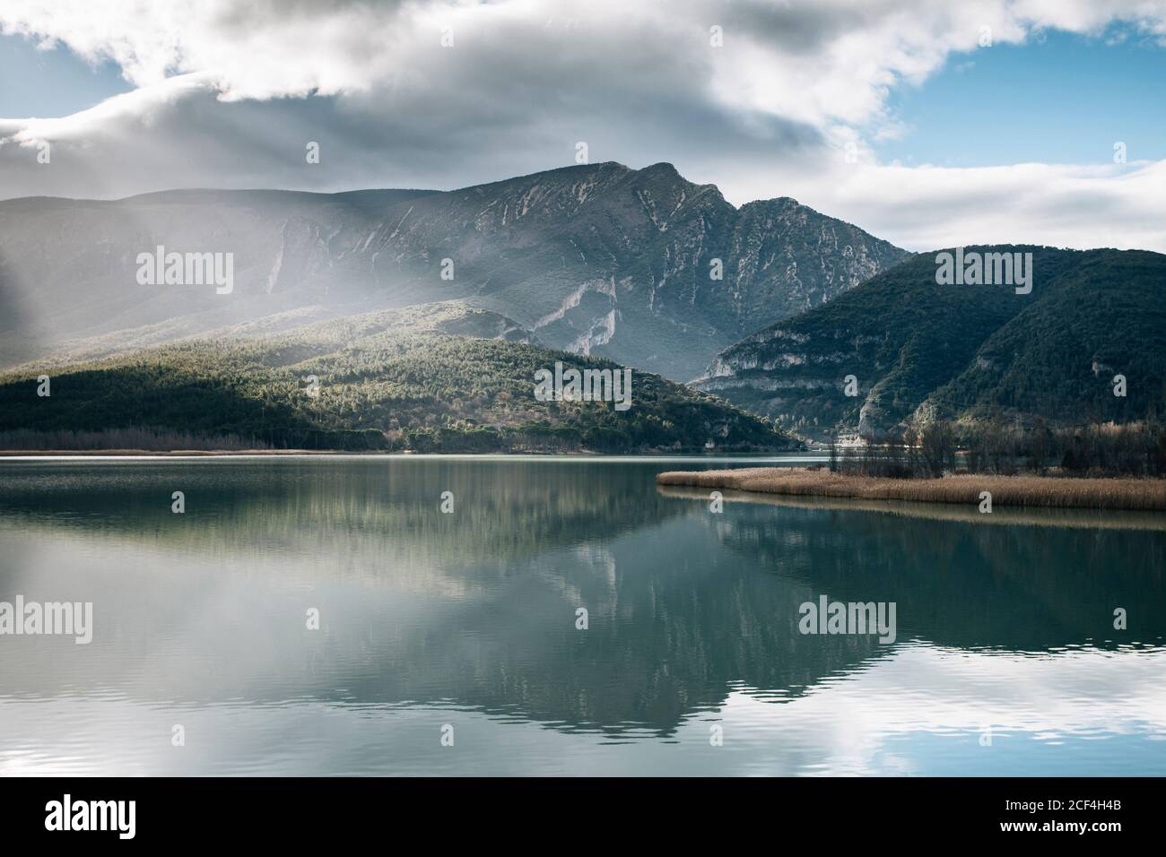 Majestic rocky mountains of Montsec Range reflected in water of calm lake in cloudy day in Spain Stock Photo