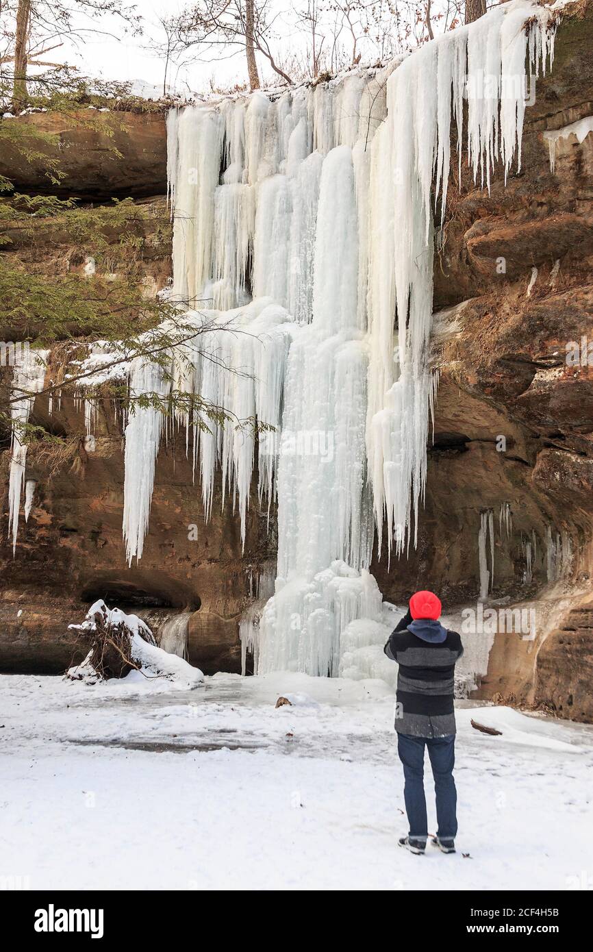 Visitor photographs frozen Lower Falls in winter at Old Man's Cave