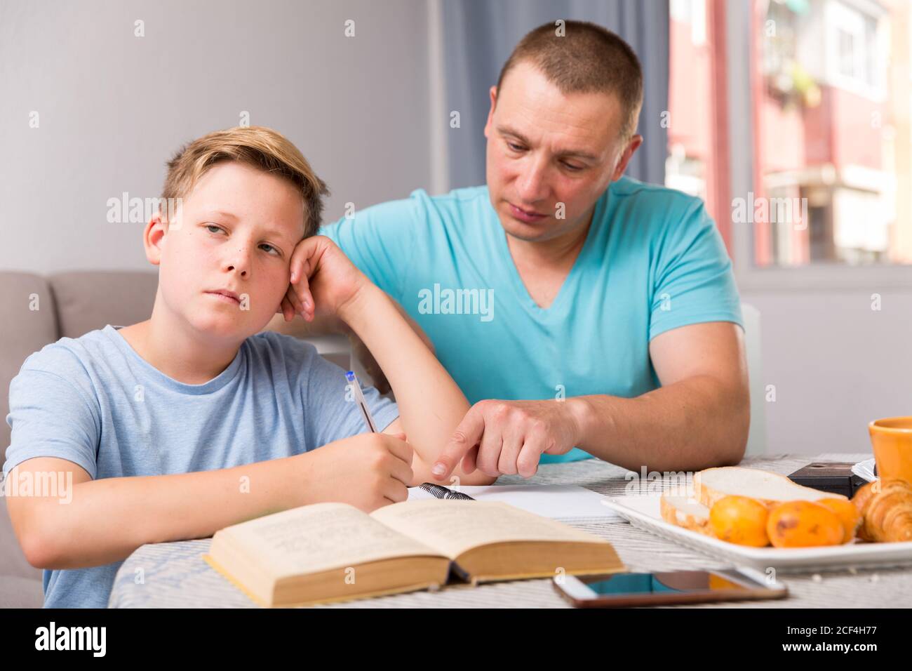 Man is offended and son is not wanting talking with him in time doing homework at the home. Stock Photo