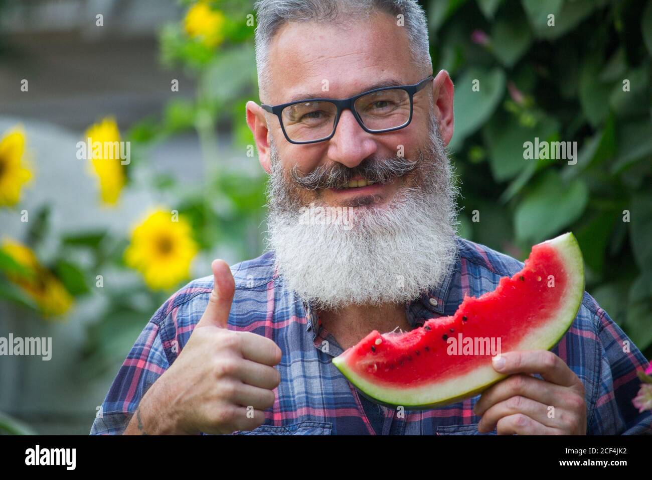 Portrait of mature bearded male farmer with ripe watermelon, own harvest concept, selective focus Stock Photo