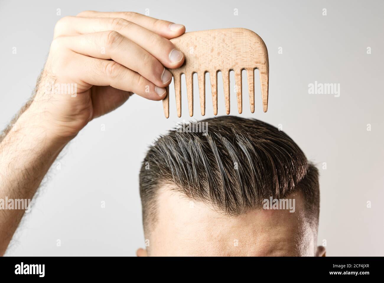 Man brushing his hair with a wooden comb and show how to take care