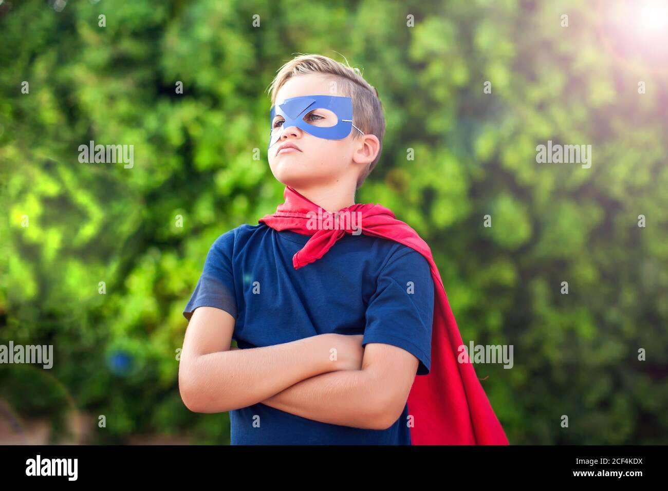 Superhero kid boy against green background outdoor. Childhood, success